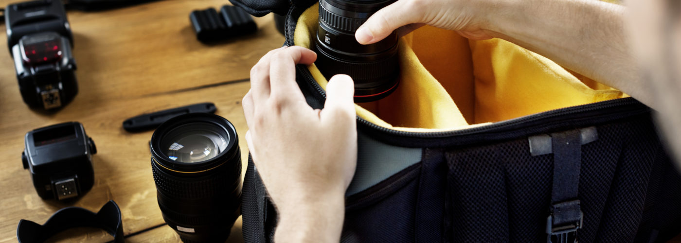 Person packing a camera bag with several lenses