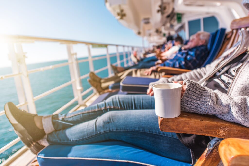 Row of cruise ship passengers relaxing on lounge chairs on the cruise deck