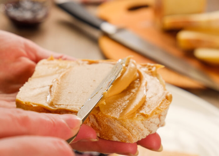 Close up of person spreading peanut butter on slice of bread
