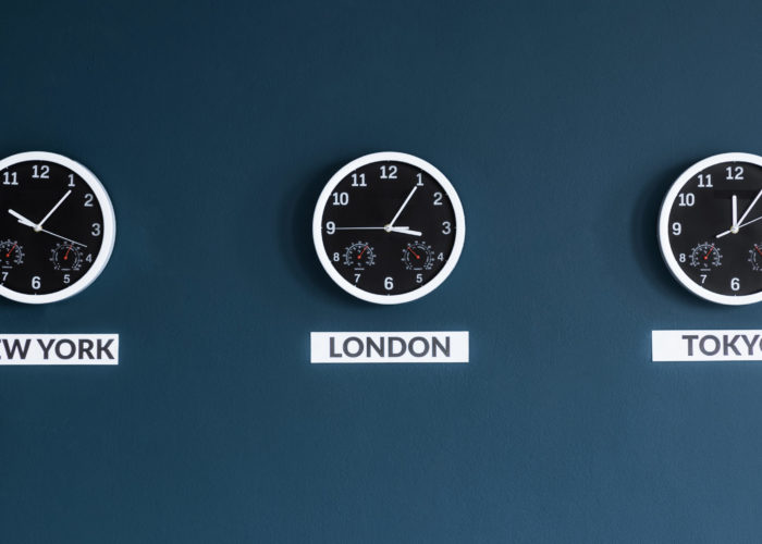 Three clocks on a dark blue wall showing the times in New York, London, and Tokyo