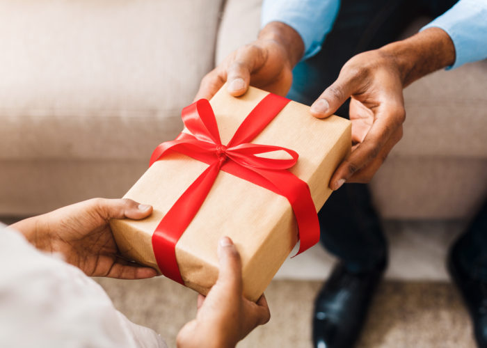 Two people exchanging a gift with a red ribbon