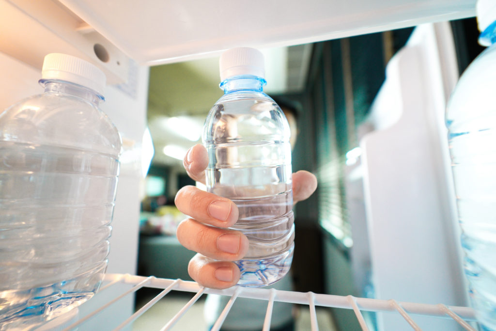 Hand taking water bottle out of fridge