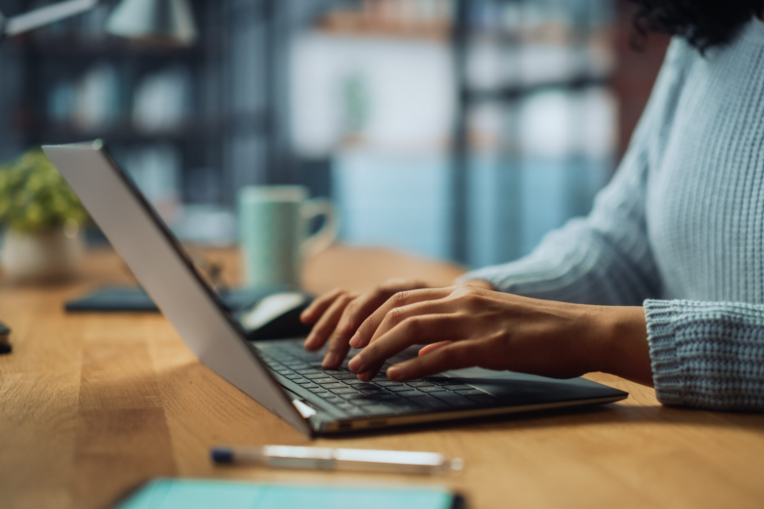 Close up of person typing on a laptop in a cozy living room