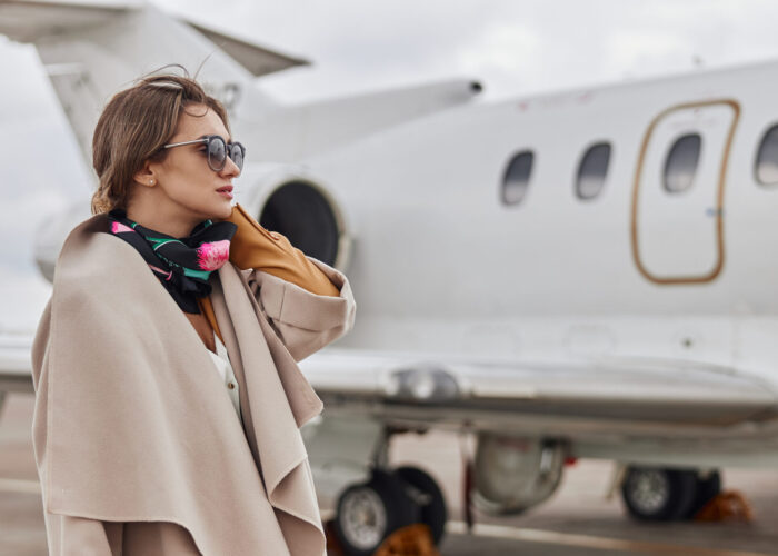 Well-dressed woman standing next to a jet plane