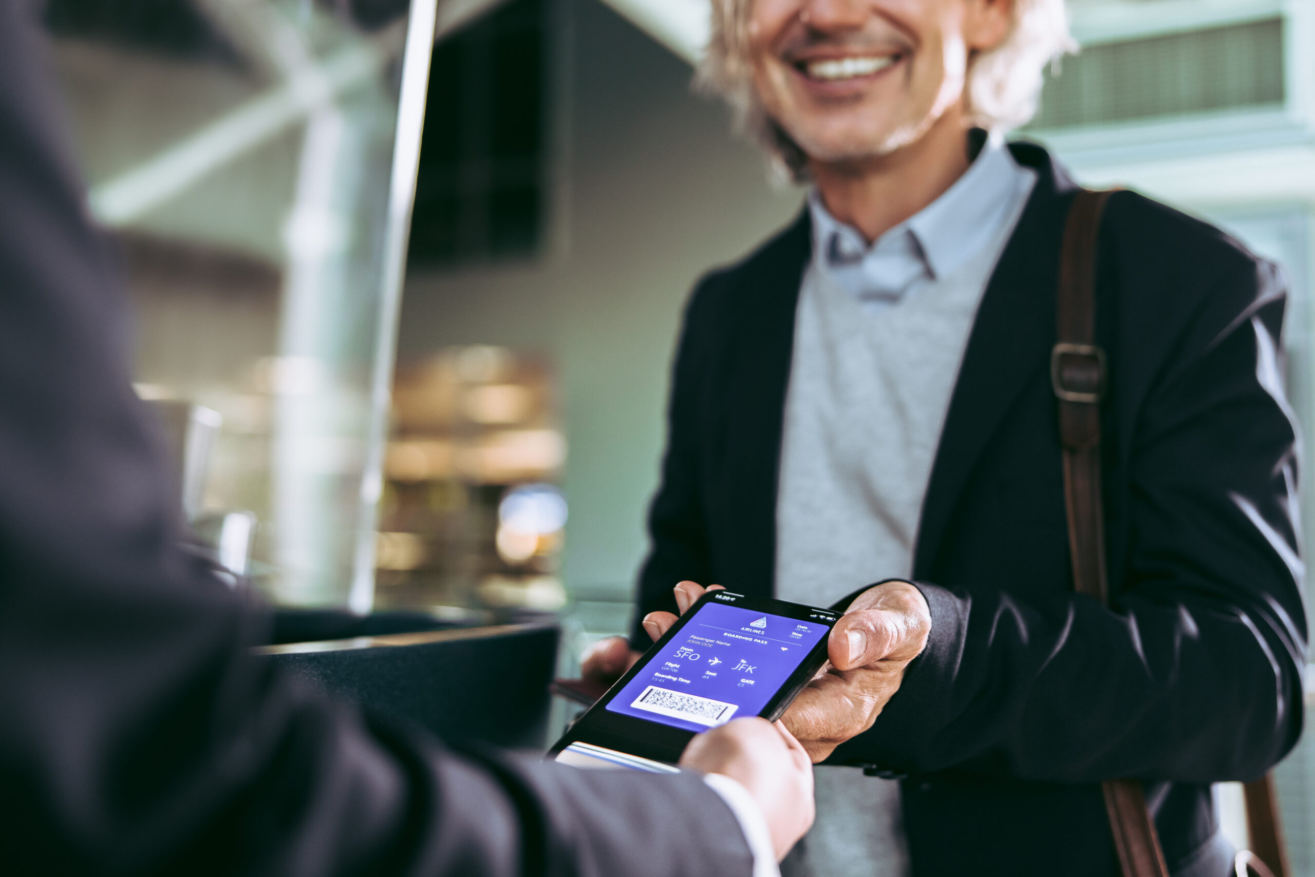 Person handing smartphone with digital boarding pass to a gate agent