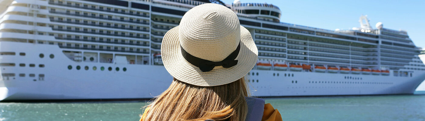 Person, as seen from behind, looking out at a docked cruise ship