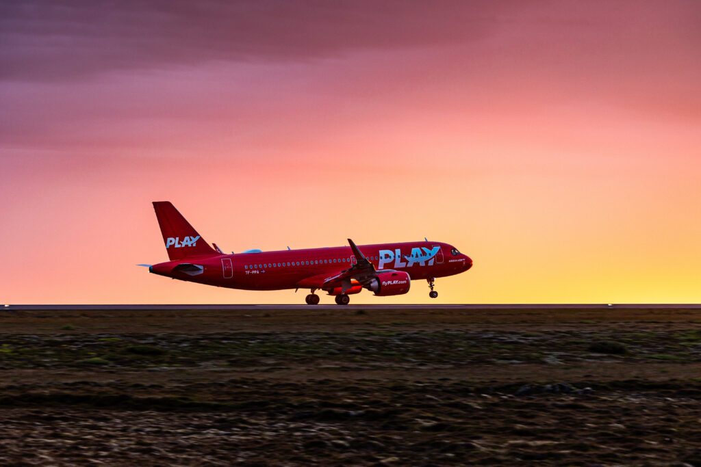 Airplane from PLAY Air fleet taking off at sunset