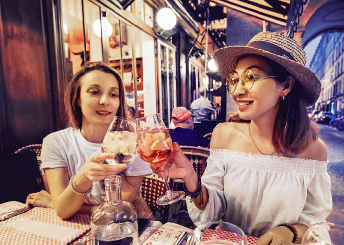 Two mixed race girls friends clinking glasses while enjoying an celebrating moment in cafe at evening time