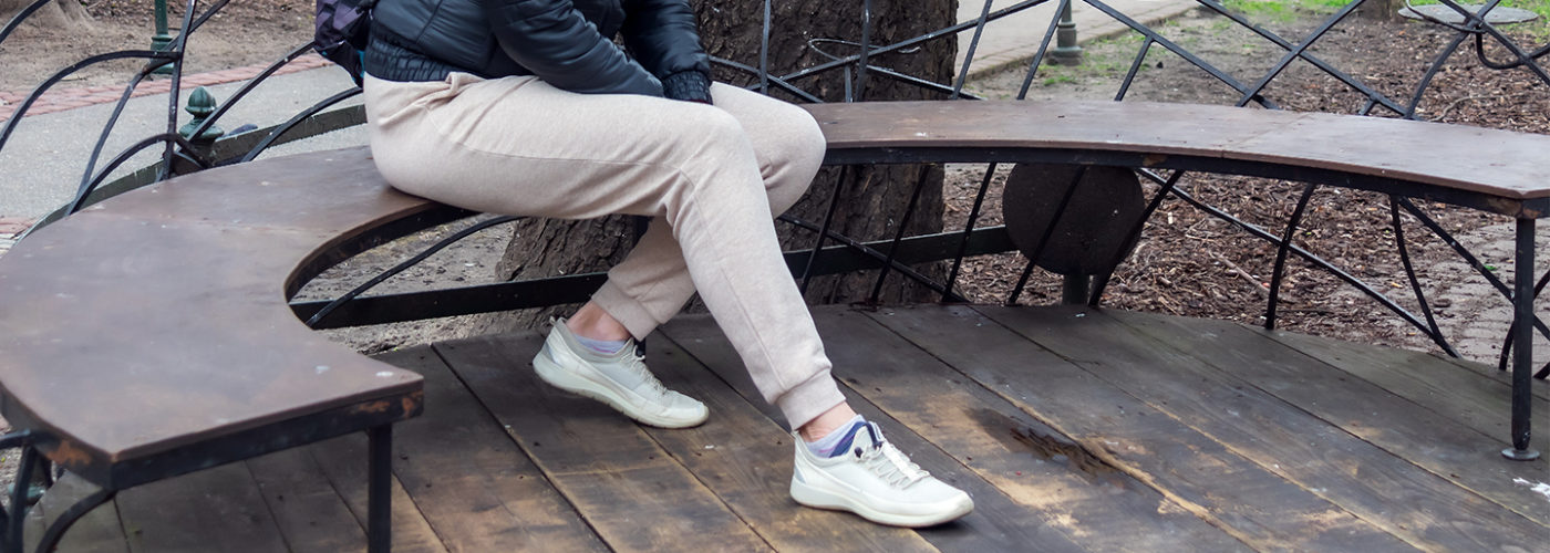 Woman sitting on a park bench in sweatpants